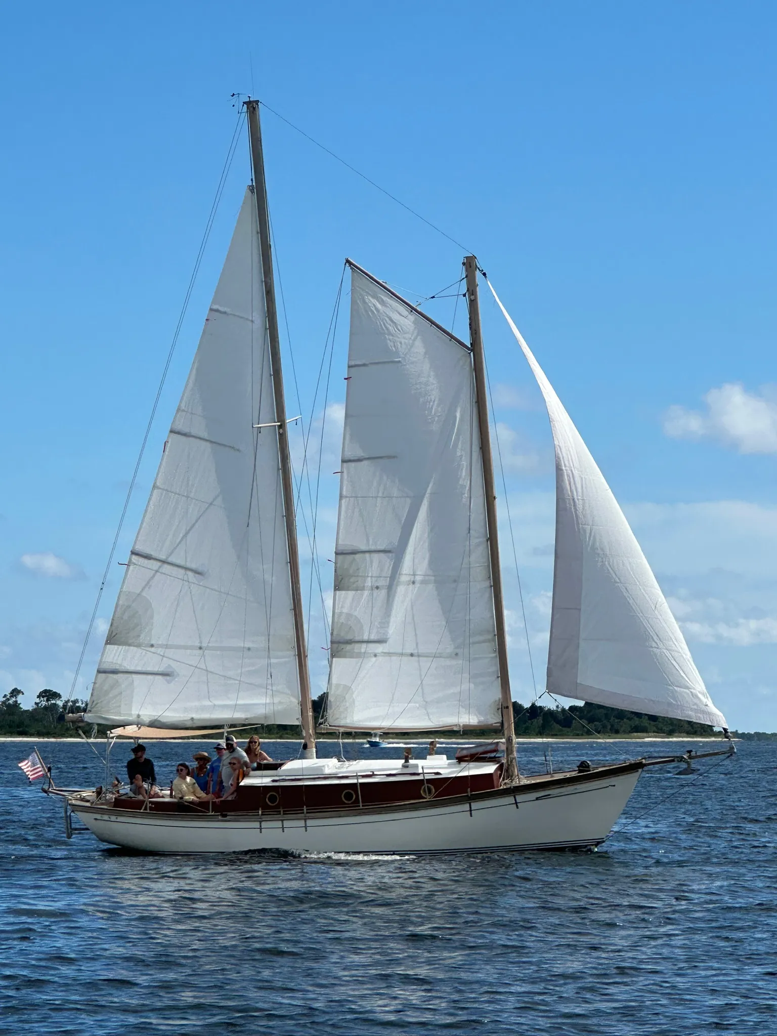 A sailboat under full sail on the Emerald Coast at golden hour